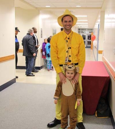 a person in yellow shirt and hat standing next to a child in a garment