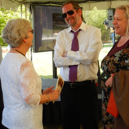 a person in a white shirt and tie talking to a group of women