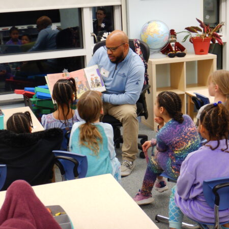 a person reading a book to a group of children