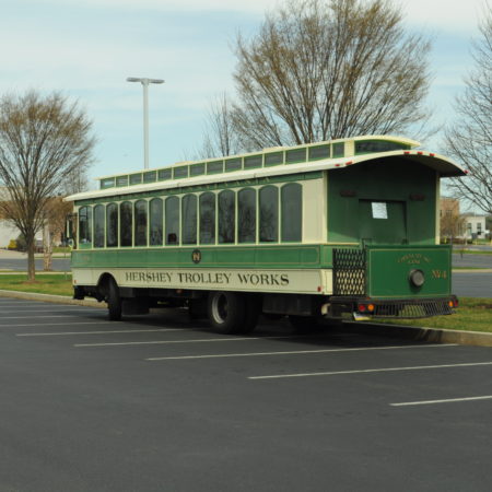 a green and white trolley in a parking lot