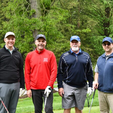 a group of men standing on a golf course