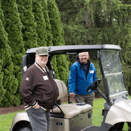 a group of men standing next to a golf cart