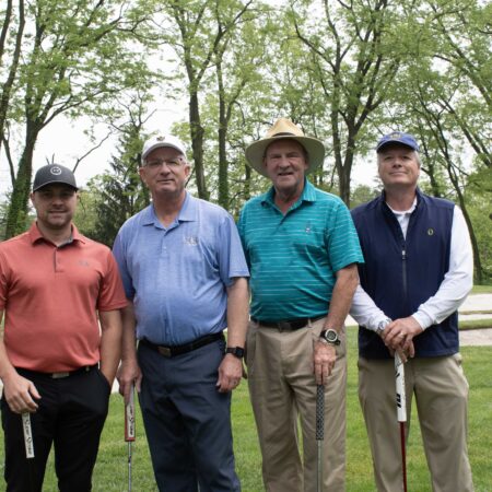 a group of men standing on a golf course