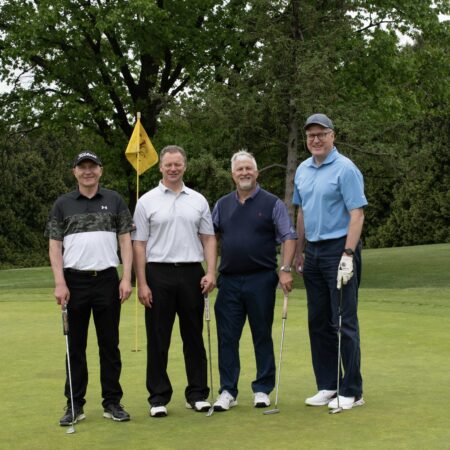a group of men standing on a golf course