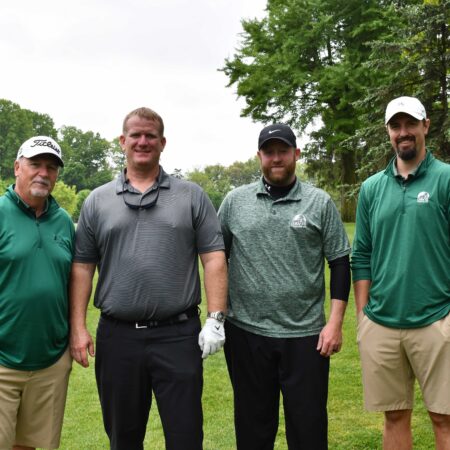 a group of men standing on a golf course