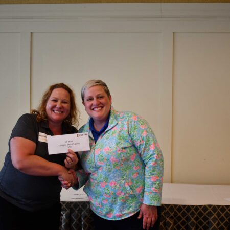 two women shaking hands with a check