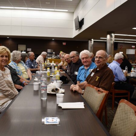 a group of people sitting at a long table