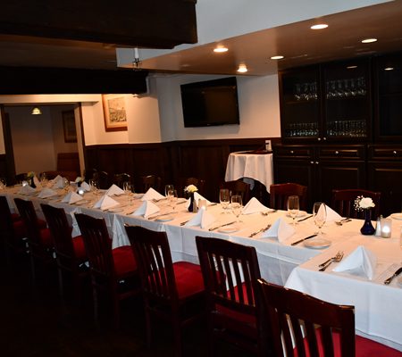 a long table with white tablecloths and red chairs