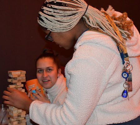 a person in a white sweater playing with a stack of wood blocks