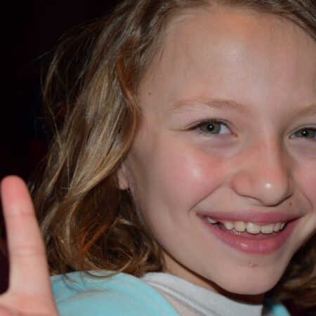 a child smiling with her hand up