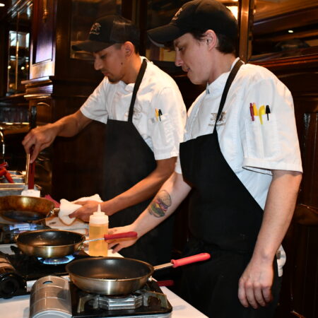 two men in aprons cooking in a kitchen