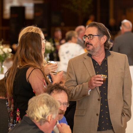 a person in a brown jacket holding a glass of wine