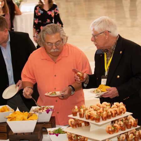a group of men standing around a table with food