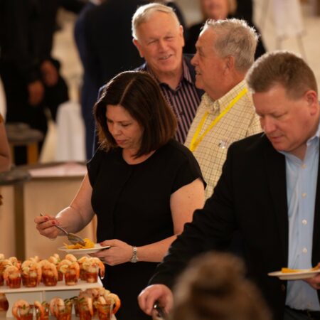 a group of people standing around a table with food