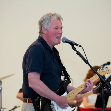 a person playing guitar and singing into a microphone