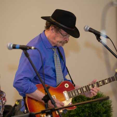 a person playing guitar in front of microphones