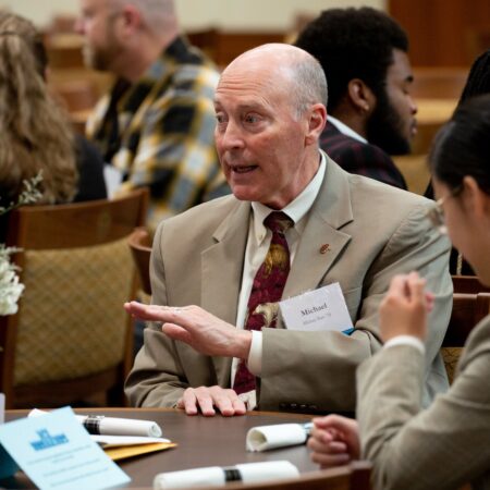 a person in a suit talking to a group of people