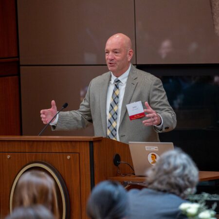 a person standing at a podium with his hands up