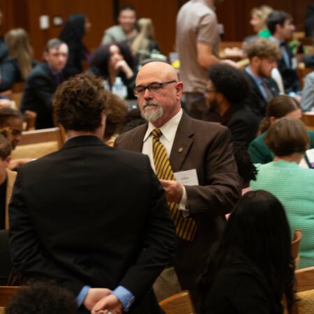 a person in a suit talking to a group of people