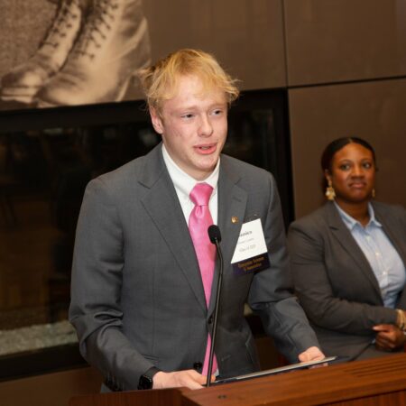 a person in a suit and tie standing at a podium