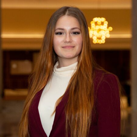 a person with long hair wearing a maroon jacket