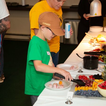 a person and child standing next to a table with food
