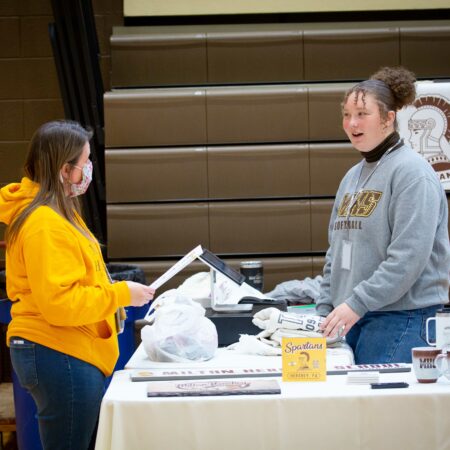 a person standing next to a person at a table