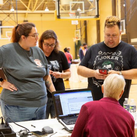 a group of people standing around a laptop