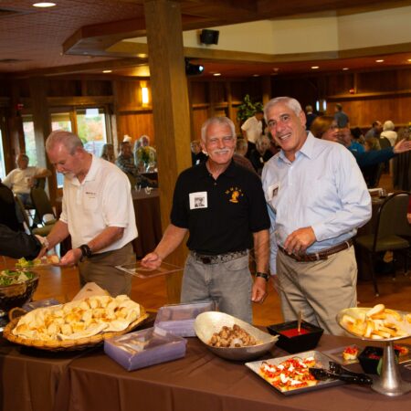 a group of men standing in front of a table full of food