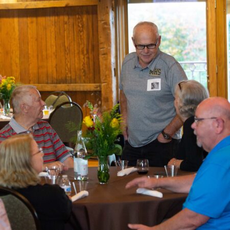 a person standing at a table with people around it