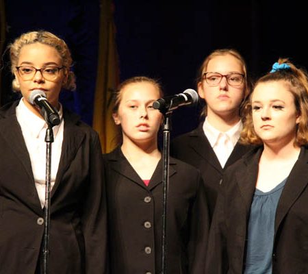 a group of young women singing into microphones