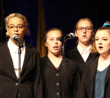 a group of children singing into microphones