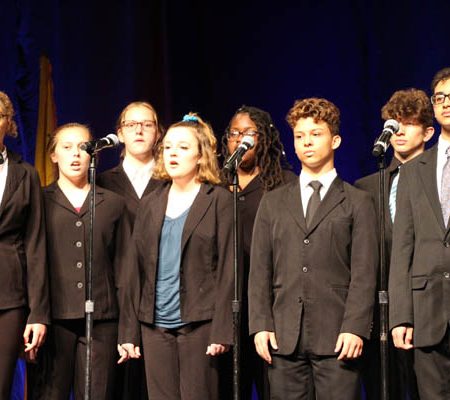 a group of people singing on stage