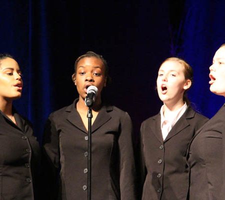 a group of women singing into a microphone