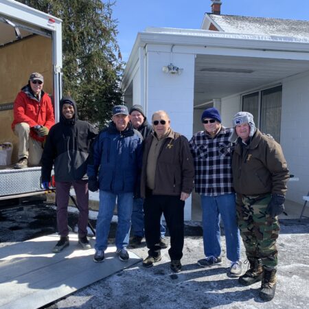 a group of men standing in front of a house