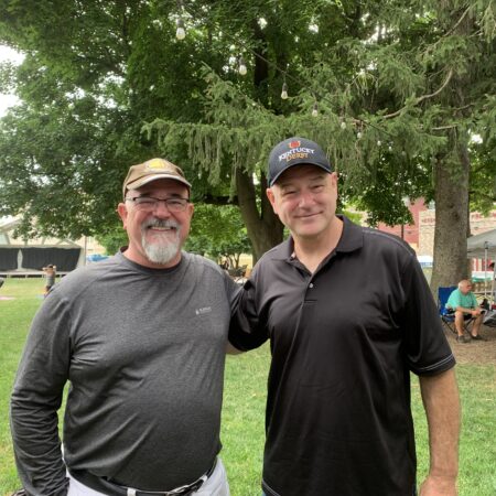 two men standing together in a park