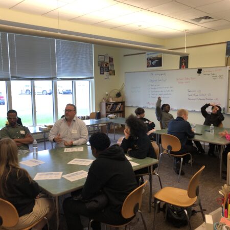 a group of people sitting at tables in a classroom