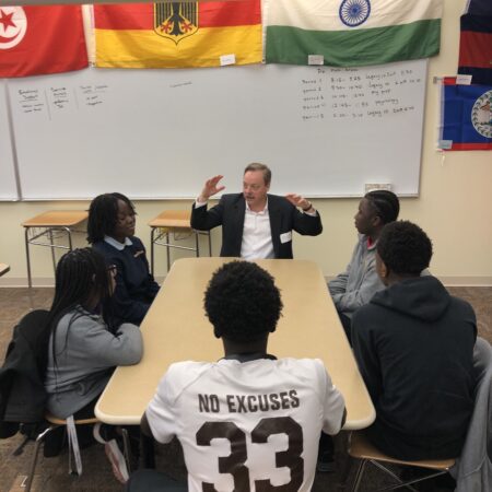 a person in a suit speaking to a group of people