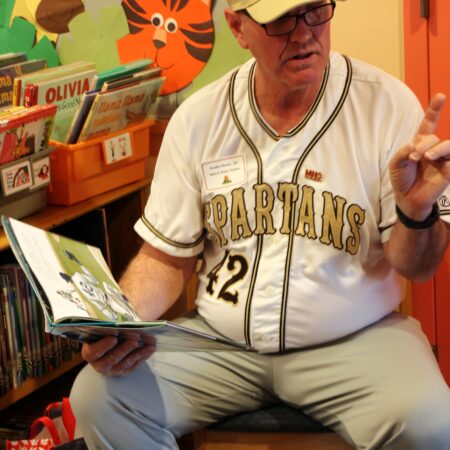a person sitting on a stool reading a book