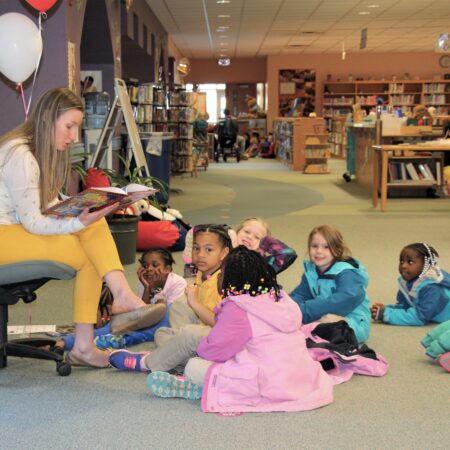 a person reading a book to children in a library