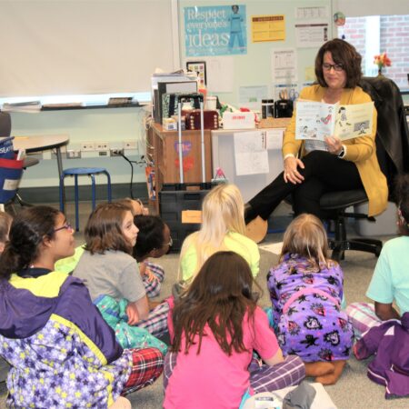 a teacher reading a book to a group of children