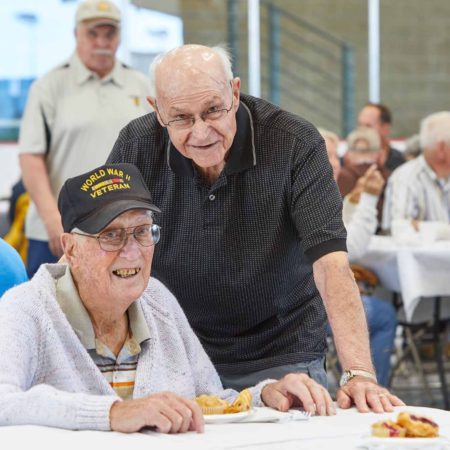 a person standing next to a person at a table