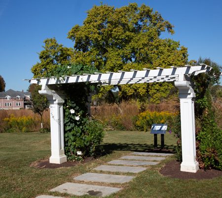 a white arbor with stone pillars and a stone path