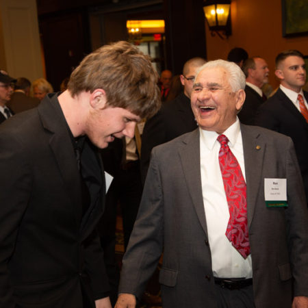 a person in a suit laughing with another person in a room