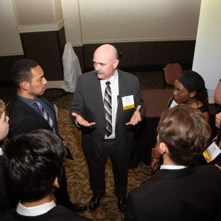a person in a suit speaking to a group of people