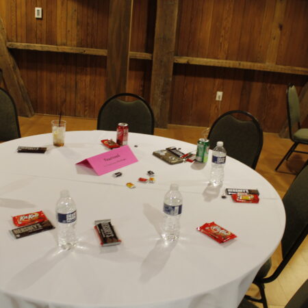 a round white table with a white tablecloth and a white tablecloth with a pink card and a pink note