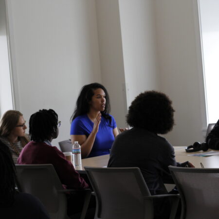 a person in a blue shirt speaking to a group of people