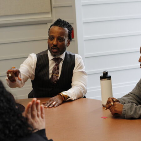 a person in a vest and tie sitting at a table