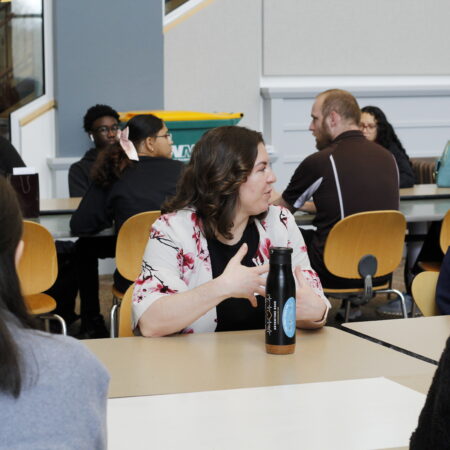 a person sitting at a table with a bottle of soda