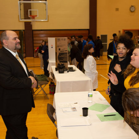 a person in a suit talking to a group of people